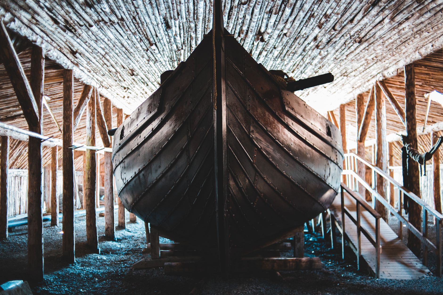 Low angle of reproduction of wooden Viking ship moored in old boathouse in Norstead Village in Newfoundland